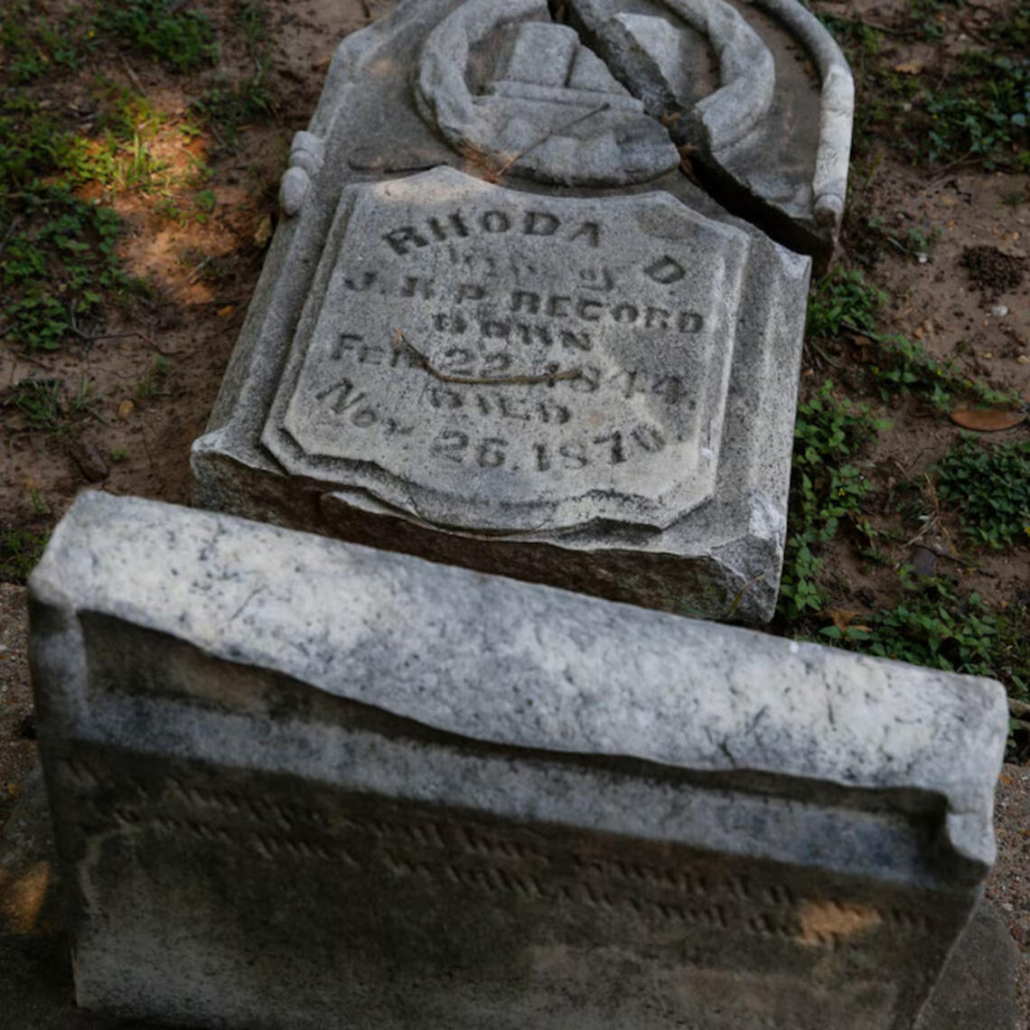 a gravestone lies on it's back showing the neglect of the pioneer park cemetery